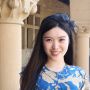 Portrait of Carina Hong with ribbon in her hair and columns in the background. 