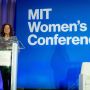 Photo of MITAA President Natalie Lorenz-Anderson standing at a podium during the MIT Women's Conference with the blue branding in the background