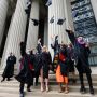 A group of graduates toss their caps into the air on the steps of Killian court