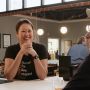 Jennifer Yang stands in her craft distillery's tasting room in Westminster, Maryland. She smiles with her elbows on the bar and her hands clasped. Behind Yang, you can see more of the restored historic venue. You can glimpse part of the company t-shirt Yang is pictured wearing. Vertically it reads, "Westminster." Horizontally it reads, "Moved for love, stayed for whiskey." 