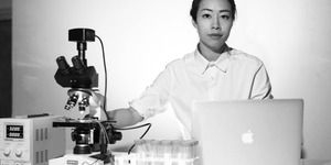 Artist Ani Liu with a microscope and laptop