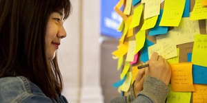 Woman writing on post-it note 