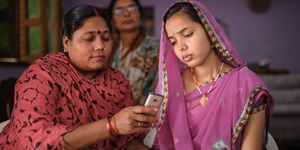 Image provided by the mobile tool Dimagi shows two women looking at a cellular photo.
