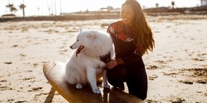 Lily Bui on a beach with her dog sitting on a surfboard