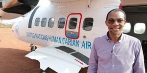 Chris Nikoi stands on a tarmac in front of a United Nations humanitarian aircraft.