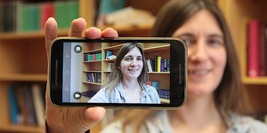 Tara Andrews holding a smartphone, with her face visible through the screen display