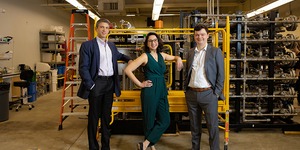Three people in business attire posing in a warehouse 