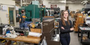Caitlin Braun stands in a large industrial space with manufacturing tools 