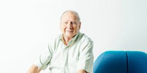 Hal Abelson sitting in a blue chair with a white background 