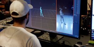 A student in a white ballcap looks at a screen showing a model human figure at left and a person at right with glowing dots on the body.