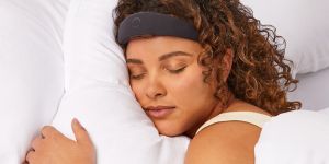 Closeup of a woman sleeping showing her head on a pillow with a black headband across her forehead.