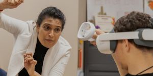 Anurupa Ganguly gestures while helping a student wearing VR goggles.