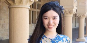 Portrait of Carina Hong with ribbon in her hair and columns in the background. 