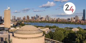 Aerial view of MIT dome with Charles River and Boston visible in the distance. Layered on top is a white circle with the number 24.