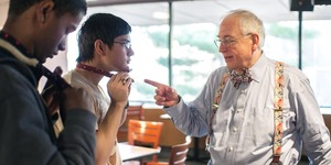 MIT alum teaches a student how to tie a bowtie