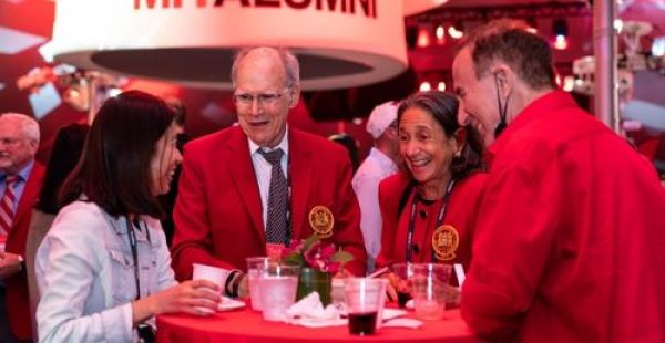 Image: Four alumni standing at a table during a Tech Reunions reception, with two individuals wearing Cardinal & Gray red jackets.