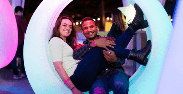 Image: Two alumni sitting in an illuminated swinging seat at Toast to Tech event