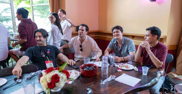 Group of alumni sitting and casually chatting around a table at The Muddy pub.