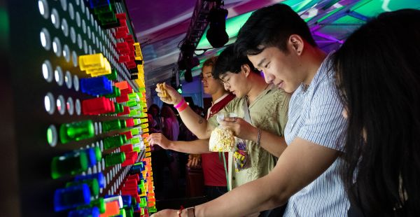 Image: group of alumni standing in front of a life size Lite-Brite game