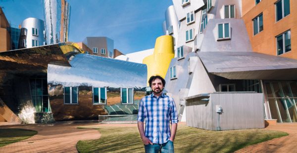 MIT alum Greg Falco standing in a courtyard outside in front of the MIT Stata Center