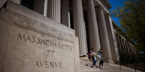 An angled view of MIT's 77 Mass Ave building showing the address carved in stone in foreground and columns in background