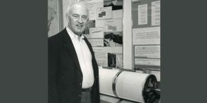 A black and white photo of MIT alum Lynn Sykes standing next to a spherical piece of equipment